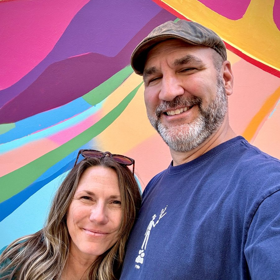 Brian and Trish in front of a colorful painted mural