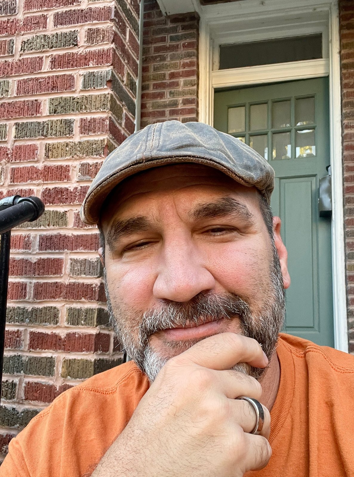 Brian Sykes in his flat cap, sitting on a brick front step